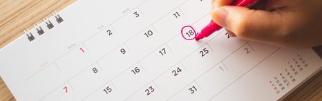 Auf einem Monatskalender umkreist eine Hand mit Filzstift einen bestimmten Tag